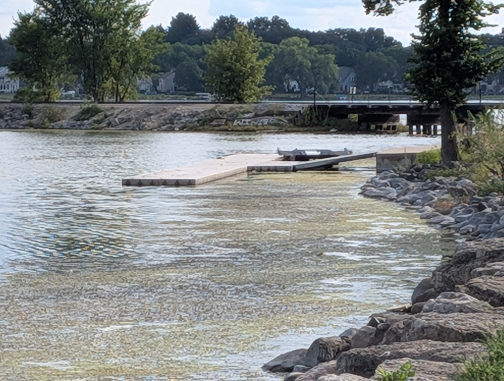 A photo of Monona Bay overlooking a floating pier and railroad tracks and Brittingham Park off the photo to the right in the distance